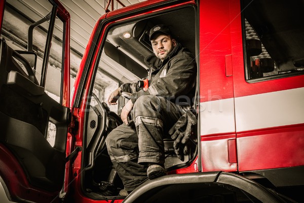 Fireman behind steering wheel of a firefighting truck  Stock photo © Nejron