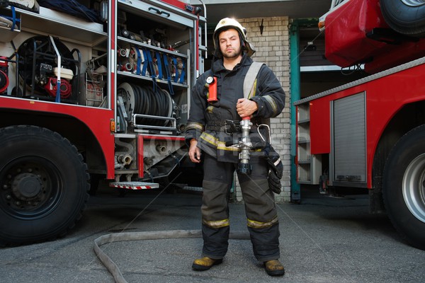 Firefighter near truck with equipment with water water hose over shoulder  Stock photo © Nejron