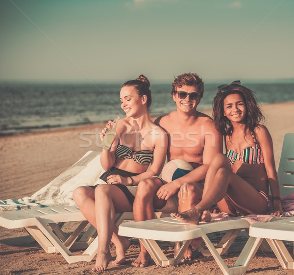 Group of multi ethnic friends sunbathing on a deck chairs on a beach  Stock photo © Nejron