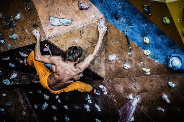 Muscular man practicing rock-climbing on a rock wall indoors  Stock photo © Nejron