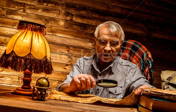 Senior man with magnifier reading vintage book in homely wooden interior  Stock photo © Nejron
