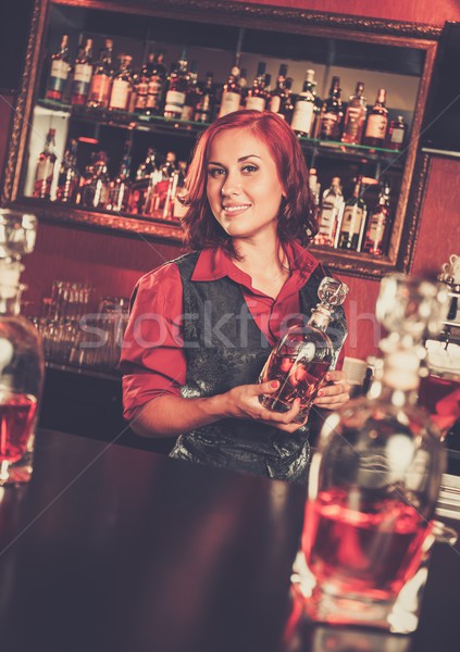 Beautiful redhead barmaid with bottle behind bar counter Stock photo © Nejron