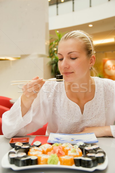 Beautiful blond girl eats sushi in a restaurant Stock photo © Nejron