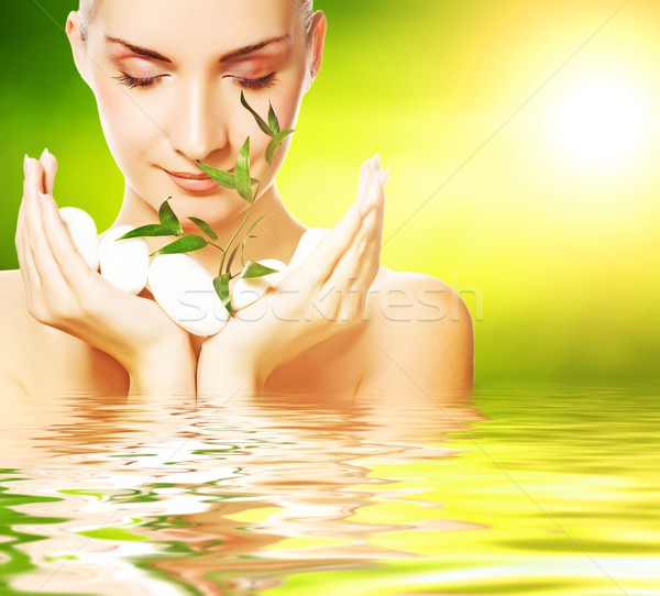 Beautiful young woman holding plant growing up through stones Stock photo © Nejron