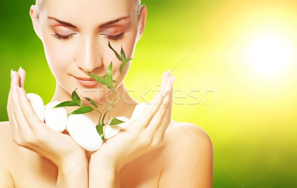 Beautiful young woman holding plant growing up through stones Stock photo © Nejron