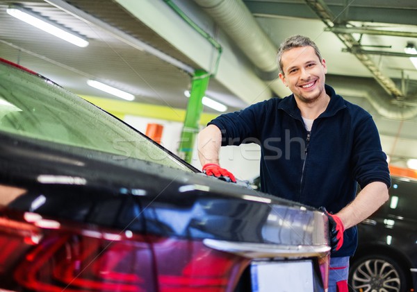 Stock photo: Cheerful worker wiping car on a car wash