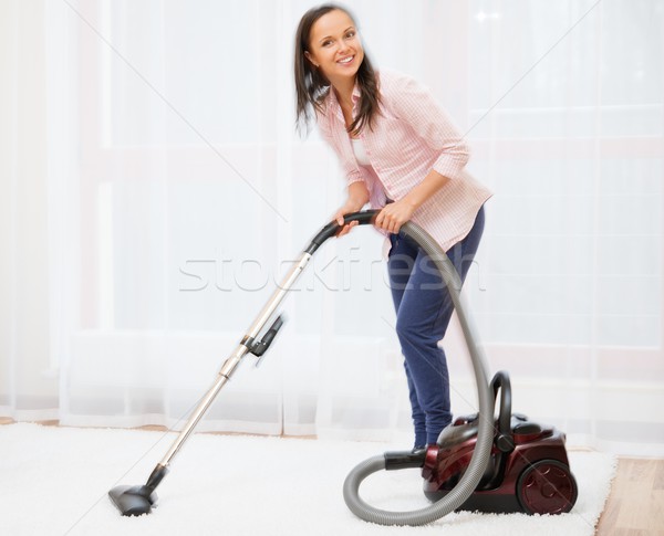 Young cheerful brunette woman vacuum cleaning carpet in home interior  Stock photo © Nejron