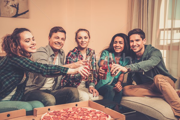Group of multi-ethnic friends with pizza and bottles of drinks having party Stock photo © Nejron