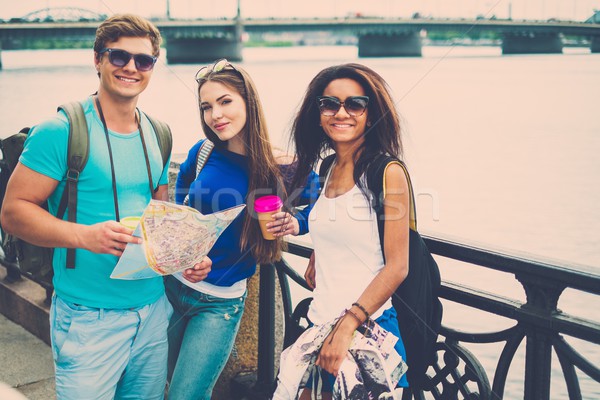 Multi-ethnic friends tourists with map and coffee cups near river in a city Stock photo © Nejron