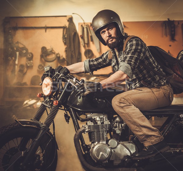 Rider and his vintage style cafe-racer motorcycle in customs garage  Stock photo © Nejron