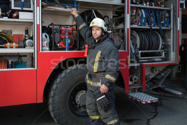 Stock photo: Fireman taking equipment from firefighting truck 