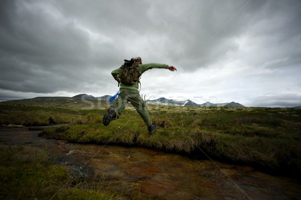 Man hiker jumping across small river Stock photo © Nejron