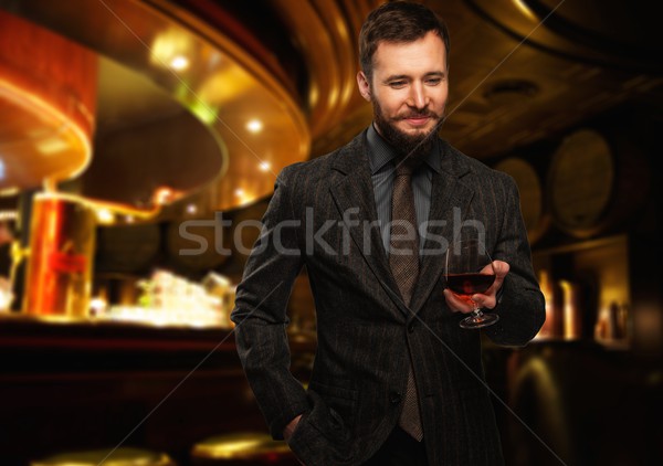 Handsome well-dressed man in jacket with glass of beverage in restaurant interior  Stock photo © Nejron