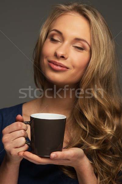 Positive young woman with long hair and blue eyes holding cup Stock photo © Nejron