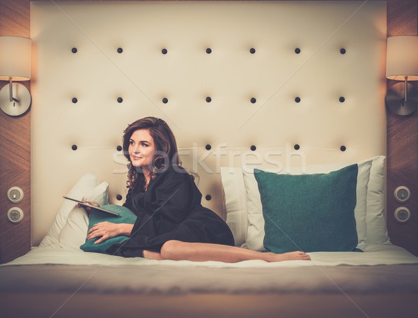 Woman in bathrobe lying on a bed with tablet pc Stock photo © Nejron