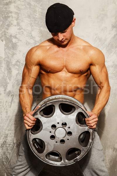 Handsome sporty man with muscular body holding alloy wheel Stock photo © Nejron