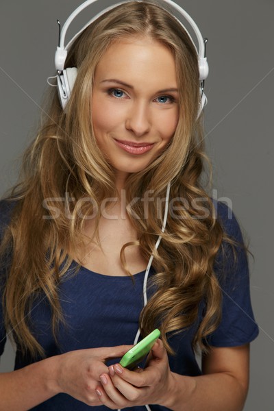 Positive young woman with long hair and blue eyes listens to music Stock photo © Nejron
