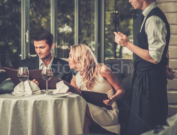 Cheerful couple with menu in a restaurant making order Stock photo © Nejron