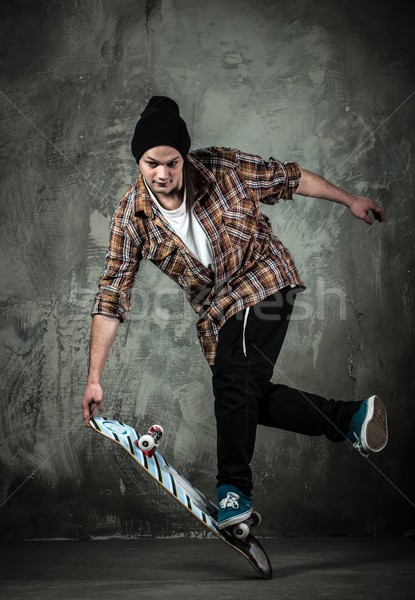 Young man in hat and shirt performing stunt on skateboard Stock photo © Nejron