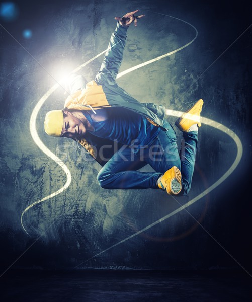 Stylish man dancer showing break-dancing moves with magic beams around him  Stock photo © Nejron