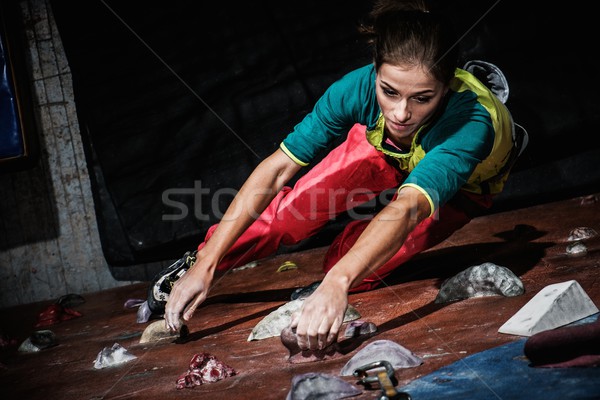 Young woman practicing rock-climbing on a rock wall indoors Stock photo © Nejron