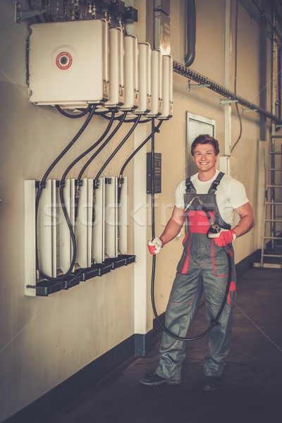 Cheerful serviceman holding hose with unbottled motor oil in a car workshop Stock photo © Nejron