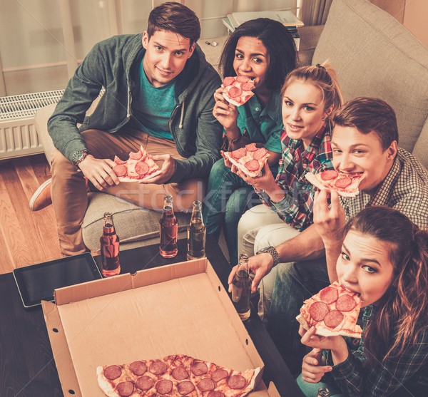 Group of multi-ethnic friends with pizza and bottles of drinks having party Stock photo © Nejron