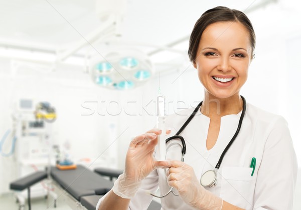 Young positive brunette doctor woman with syringe in surgery room Stock photo © Nejron