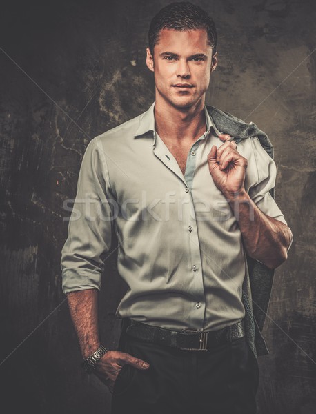 Handsome man in shirt against grunge wall holding jacket over shoulder  Stock photo © Nejron