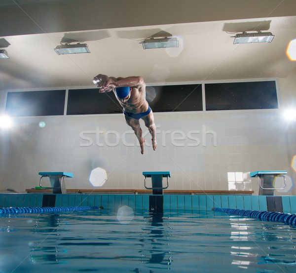 Young muscular swimmer jumping from starting block in a swimming pool Stock photo © Nejron