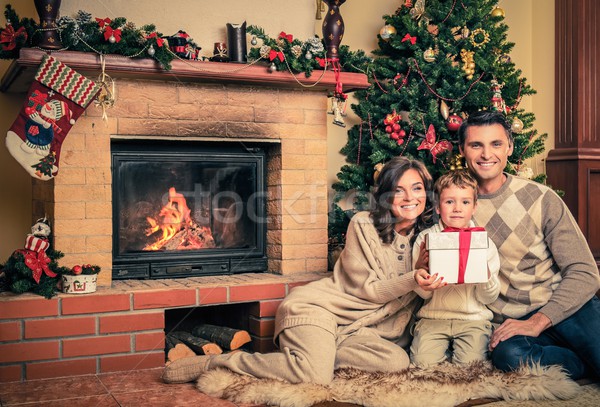 Family near fireplace in Christmas decorated house interior with gift box Stock photo © Nejron