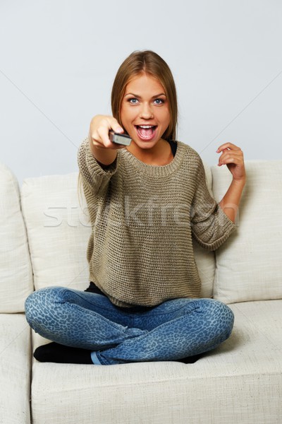 Young beautiful woman on a sofa with remote control  Stock photo © Nejron