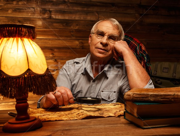 Senior man with magnifier looking at vintage map in homely wooden interior  Stock photo © Nejron