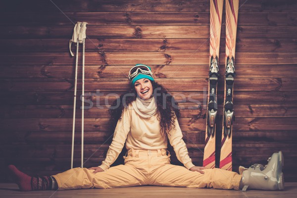 Happy woman with skis and ski boots sitting near wooden wall in snowflakes Stock photo © Nejron