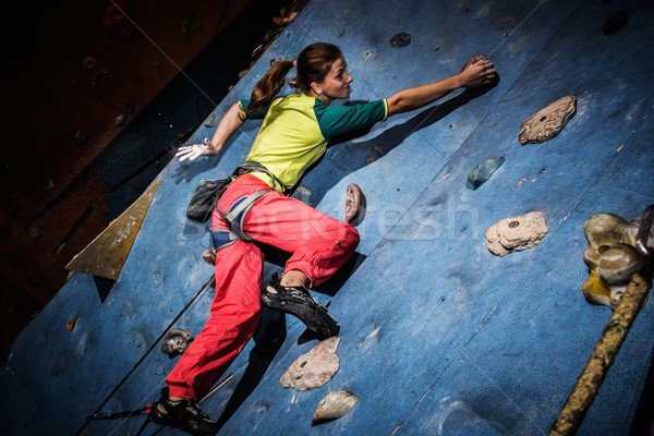 Young woman practicing rock-climbing on a rock wall indoors Stock photo © Nejron