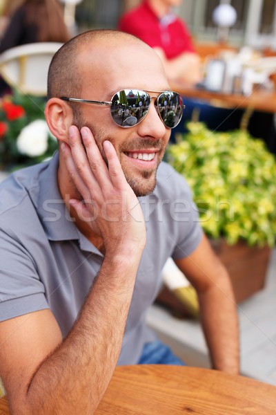 Positive middle-aged man alone behind table in summer cafe Stock photo © Nejron