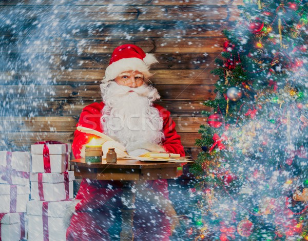 Santa Claus in wooden home interior sitting behind table and writing letters with quill pen Stock photo © Nejron