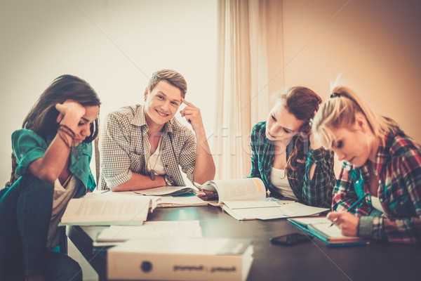 Multi ethnic group of students preparing for exams in home interior behind table  Stock photo © Nejron