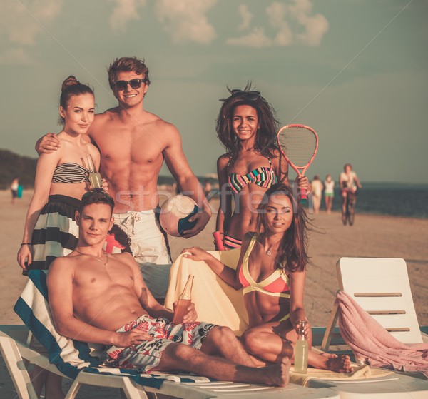 Group of multi ethnic friends with ball and racket on a beach  Stock photo © Nejron