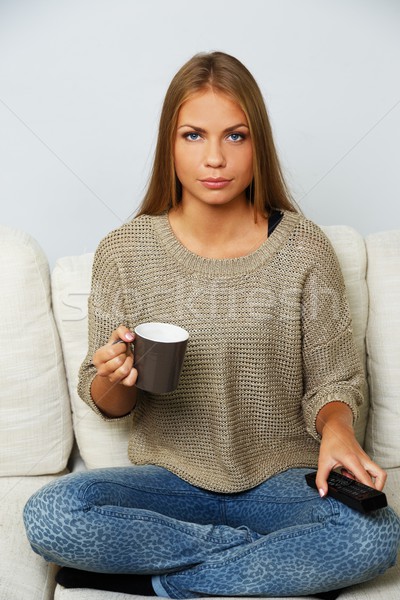 Young beautiful woman on a sofa with remote control and mug Stock photo © Nejron