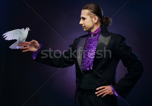 Young handsome brunette magician man in stage costume with his trained white doves Stock photo © Nejron
