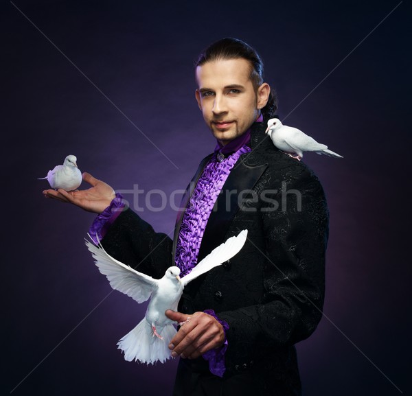 Young handsome brunette magician man in stage costume with his trained white doves Stock photo © Nejron