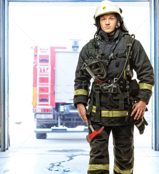 Young firefighter against truck in firefighting depot  Stock photo © Nejron