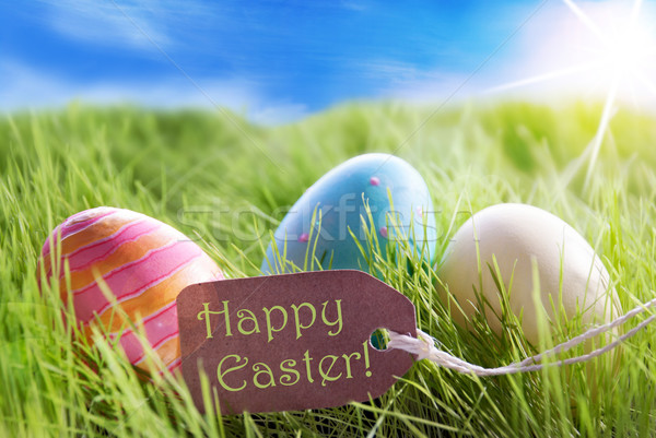 Three Colorful Easter Eggs On Sunny Green Grass With Label Happy Easter Stock photo © Nelosa