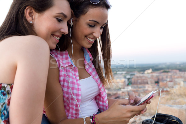 Stock photo: Beautiful girls sitting on the roof and listening to music at su