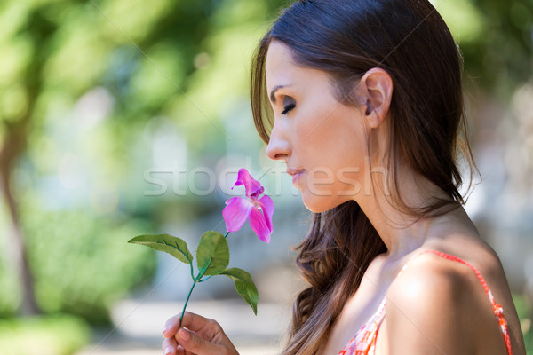 Young beautiful girl smells flowers, against green summer garden Stock photo © nenetus