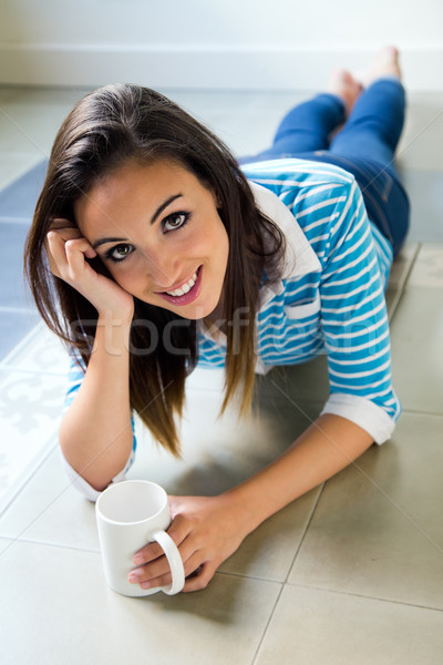 Beautiful brunette girl who is lying on the floor and drinking c Stock photo © nenetus