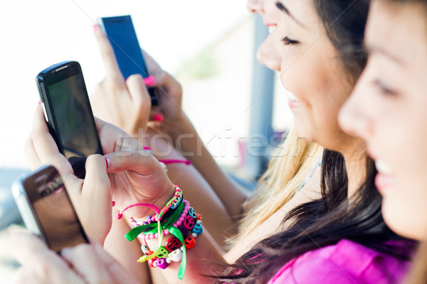 Stock photo: three girls chatting with their smartphones