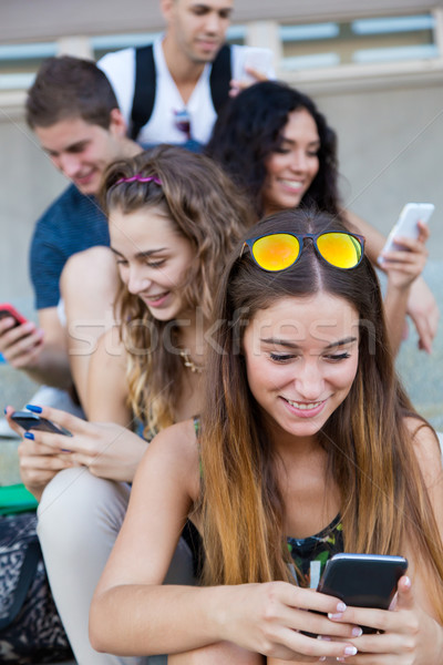 A group of students having fun with smartphones after class. Stock photo © nenetus