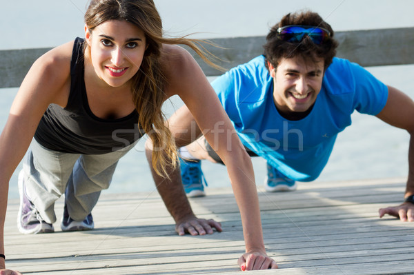 Stock photo: Couple doing push ups near the sea